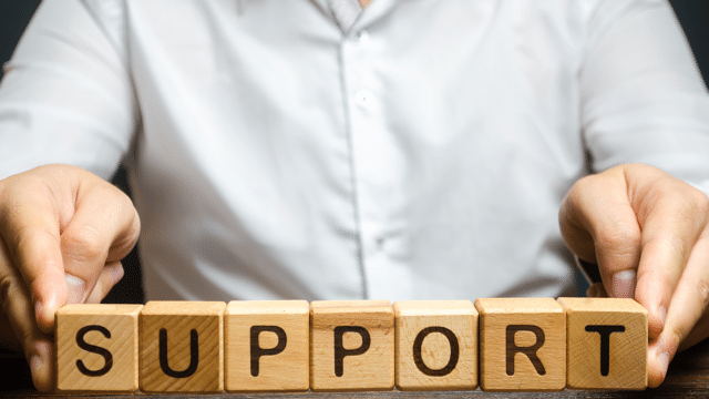 Man holding up wooden letter blocks that spells out the word support.