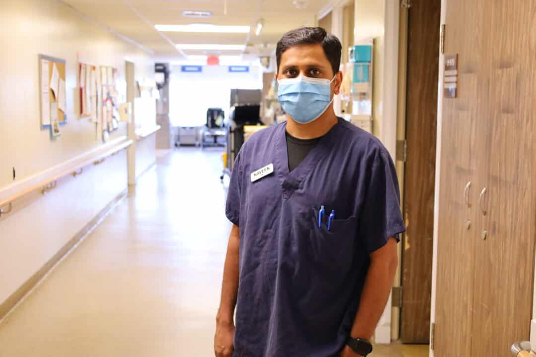 A nurse stands in the hallway of an acute medicine unit.