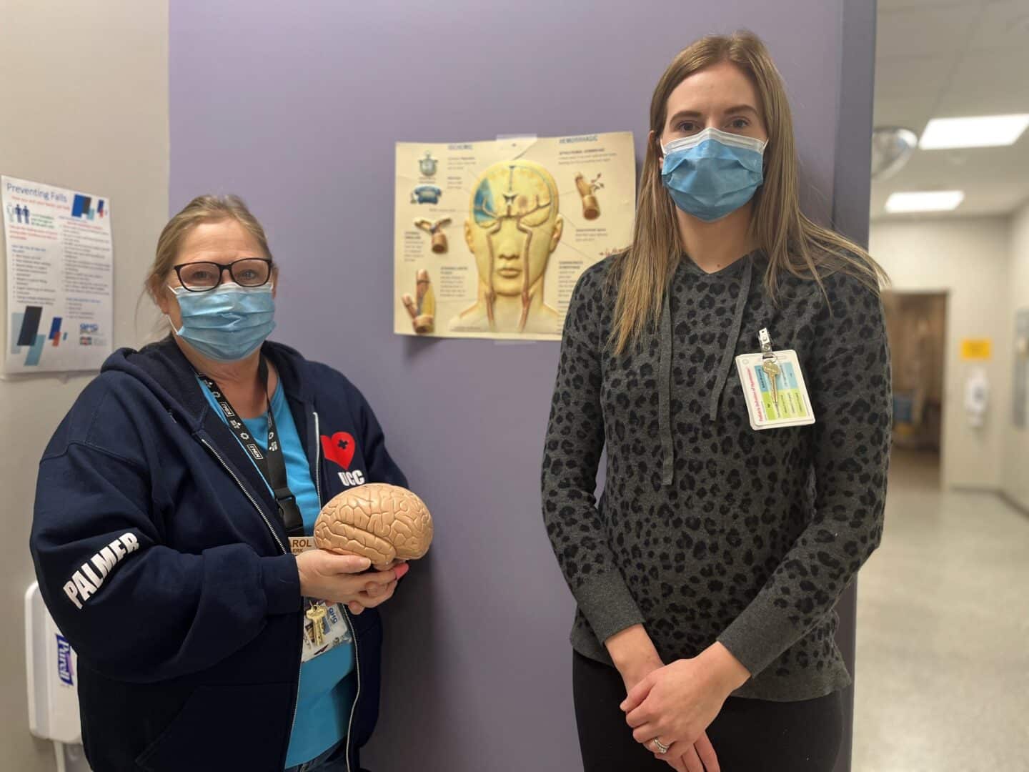 A clerk and a nurse holding a plastic brain in the stroke prevention clinic