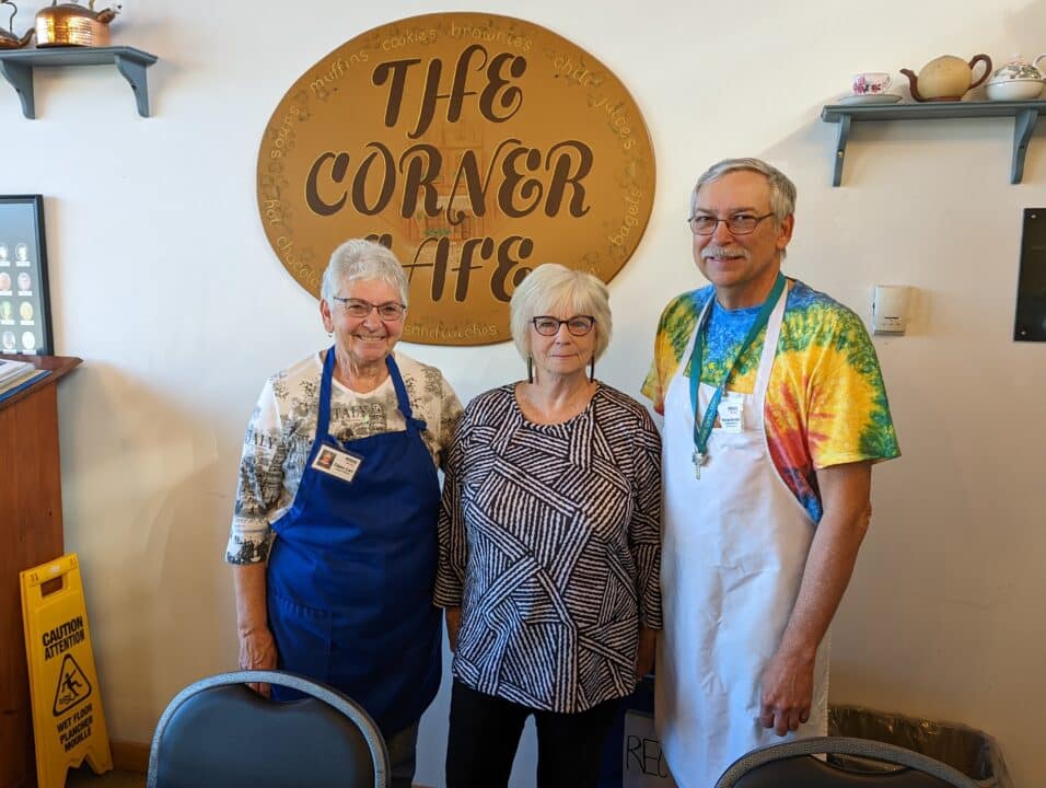 Volunteers standing together in front of the Corner Café sign.