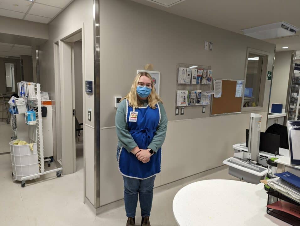 Young female volunteer, Savannah, standing near the volunteer desk in the ICU at BGH.
