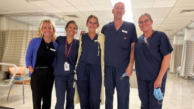 Five hospitals workers stand together and smile for the camera inside the endoscopy suite.