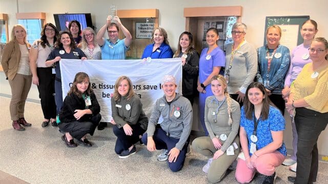 A group of hospital workers with an organ and tissue donation flag and award.