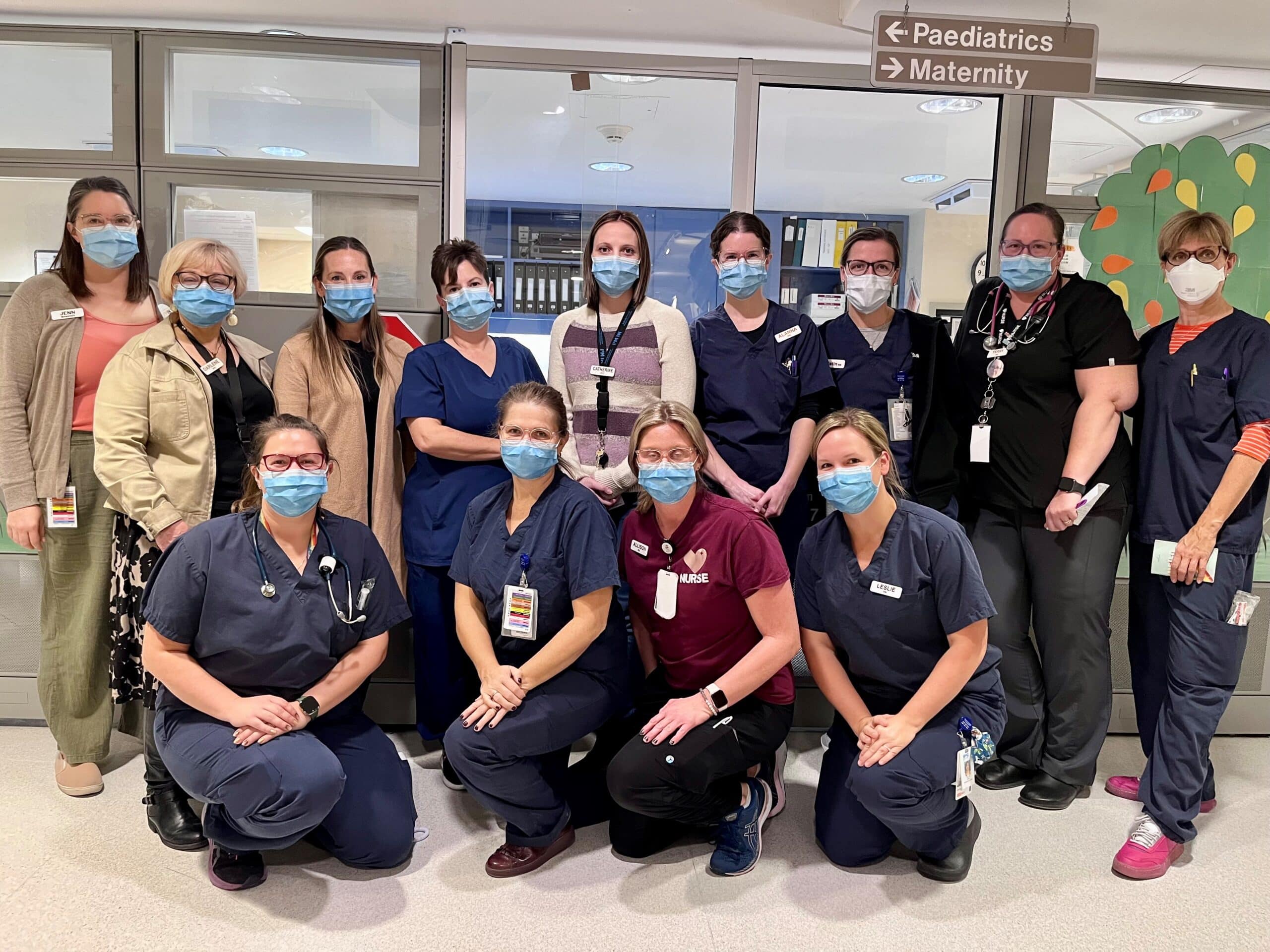 A group of 13 health care professionals wearing medical masks gathered together.